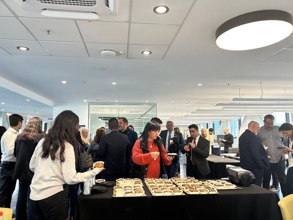Servicio de catering corporativo en el hall de una empresa, con asistentes sirviéndose de la mesa montada