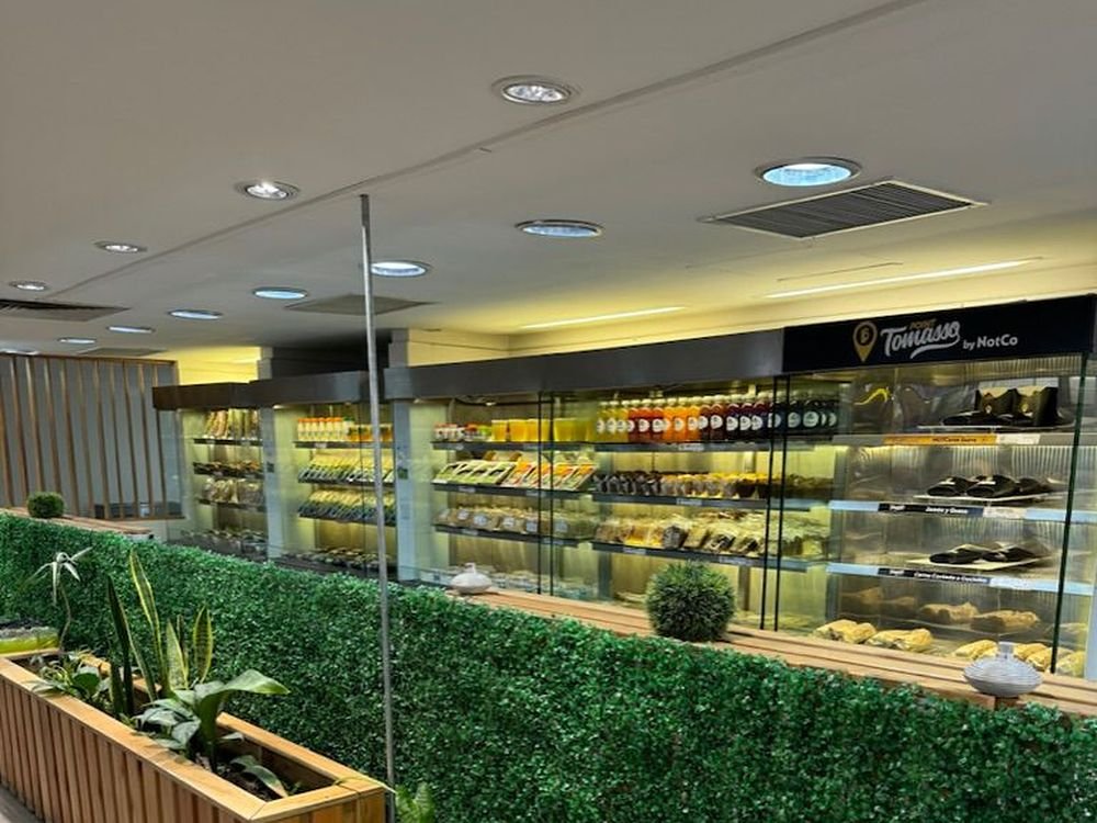 Exhibidor refrigerado de la marca Tomasso by NotCo, con muro verde y cantero de madera en el pasillo