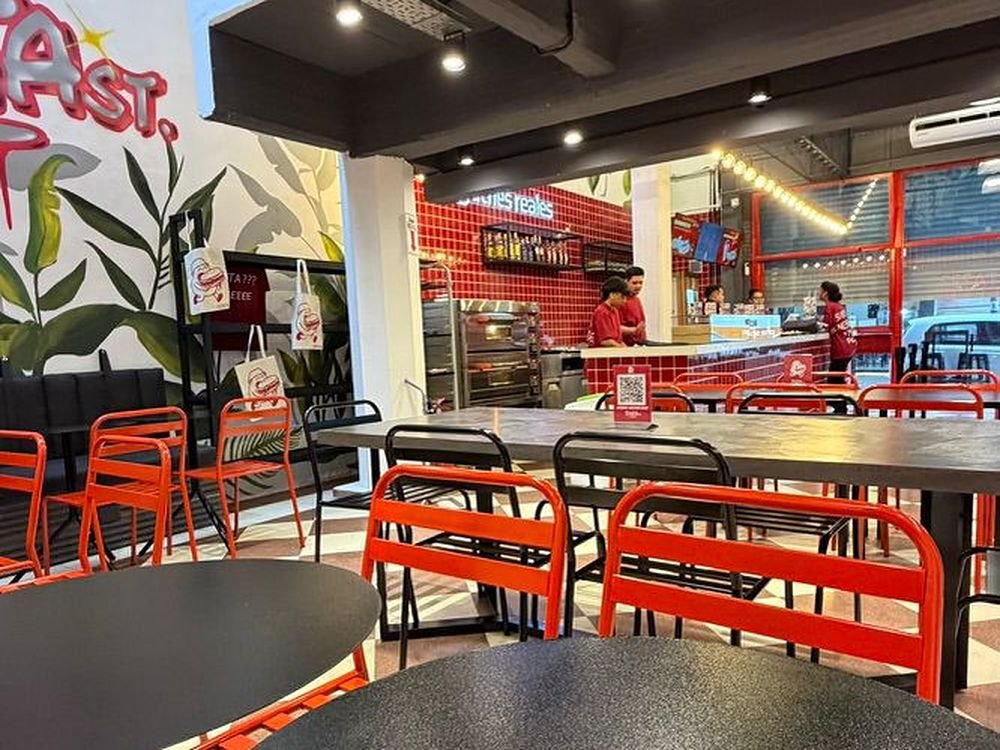 Salón de servicio rápido con mural, mobiliario rojo y barra de atención al fondo