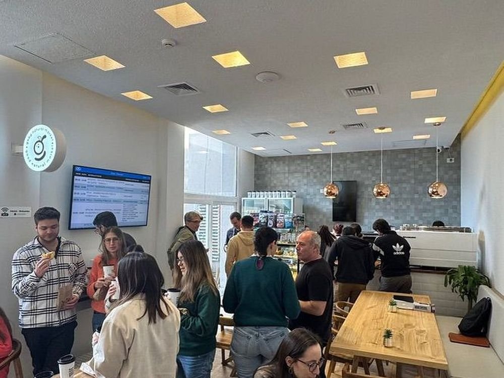 Cafetería Good Natural operada por DAF, con estudiantes atendiéndose en el mostrador y mesas ocupadas