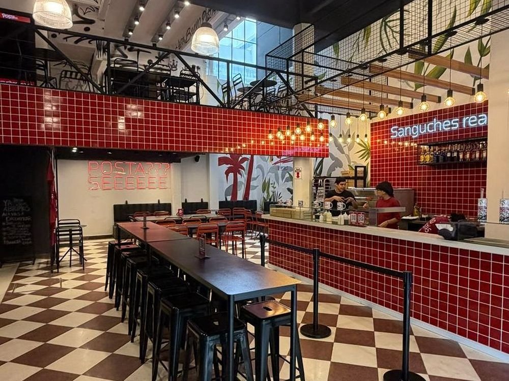 Salón de POSTA st. con revestimiento rojo, barra de atención y mesas altas