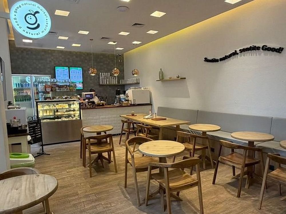 Salón de Good Natural con mesas de madera y mostrador de exhibición